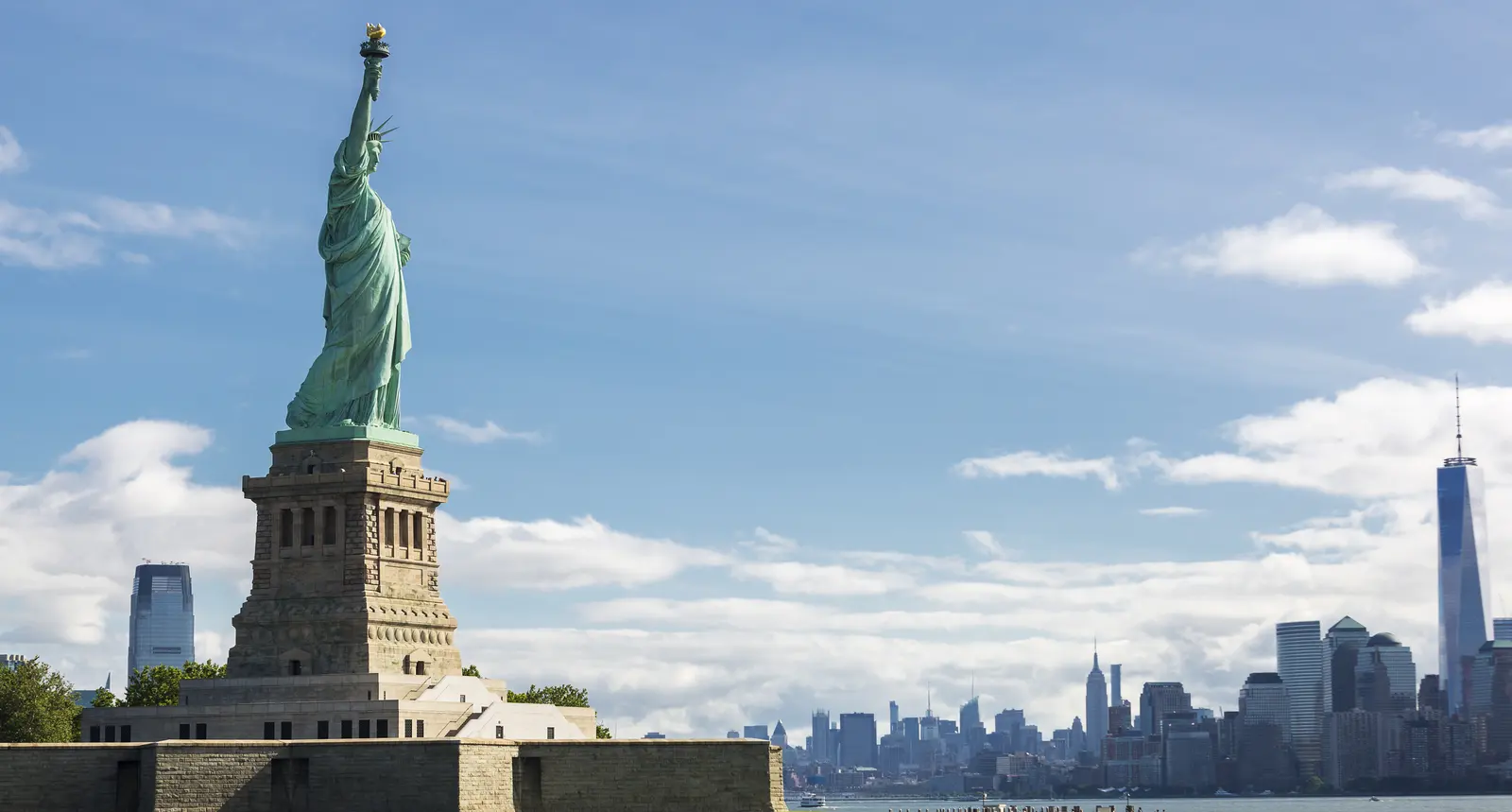 Estátua da Liberdade à luz do dia com o skyline de Nova York ao fundo
